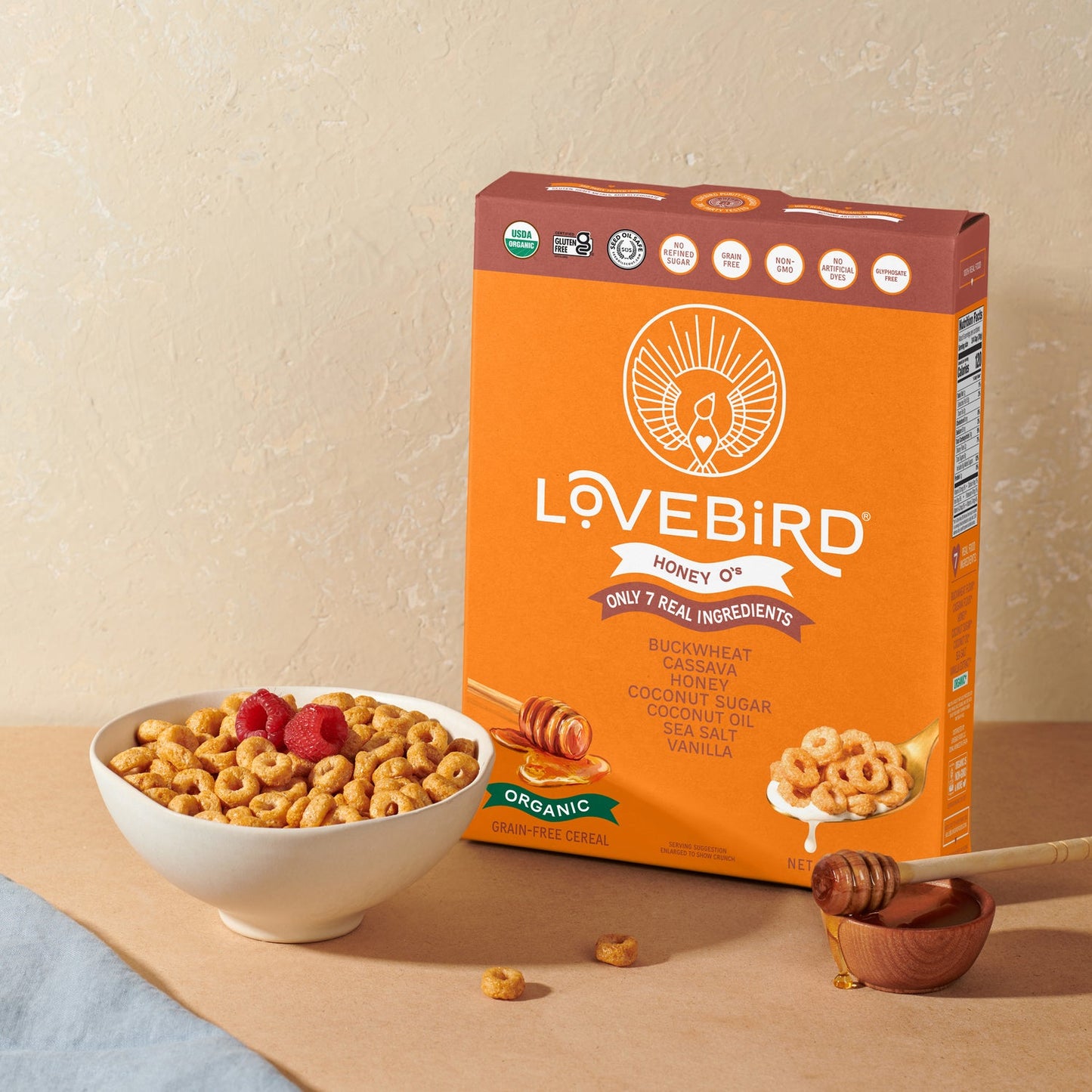Lovebird cereal box with a bowl of cereal and honey on a beige background